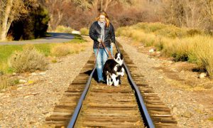 Annie Phenix and her dogs Echo and Radar walking on train tracks